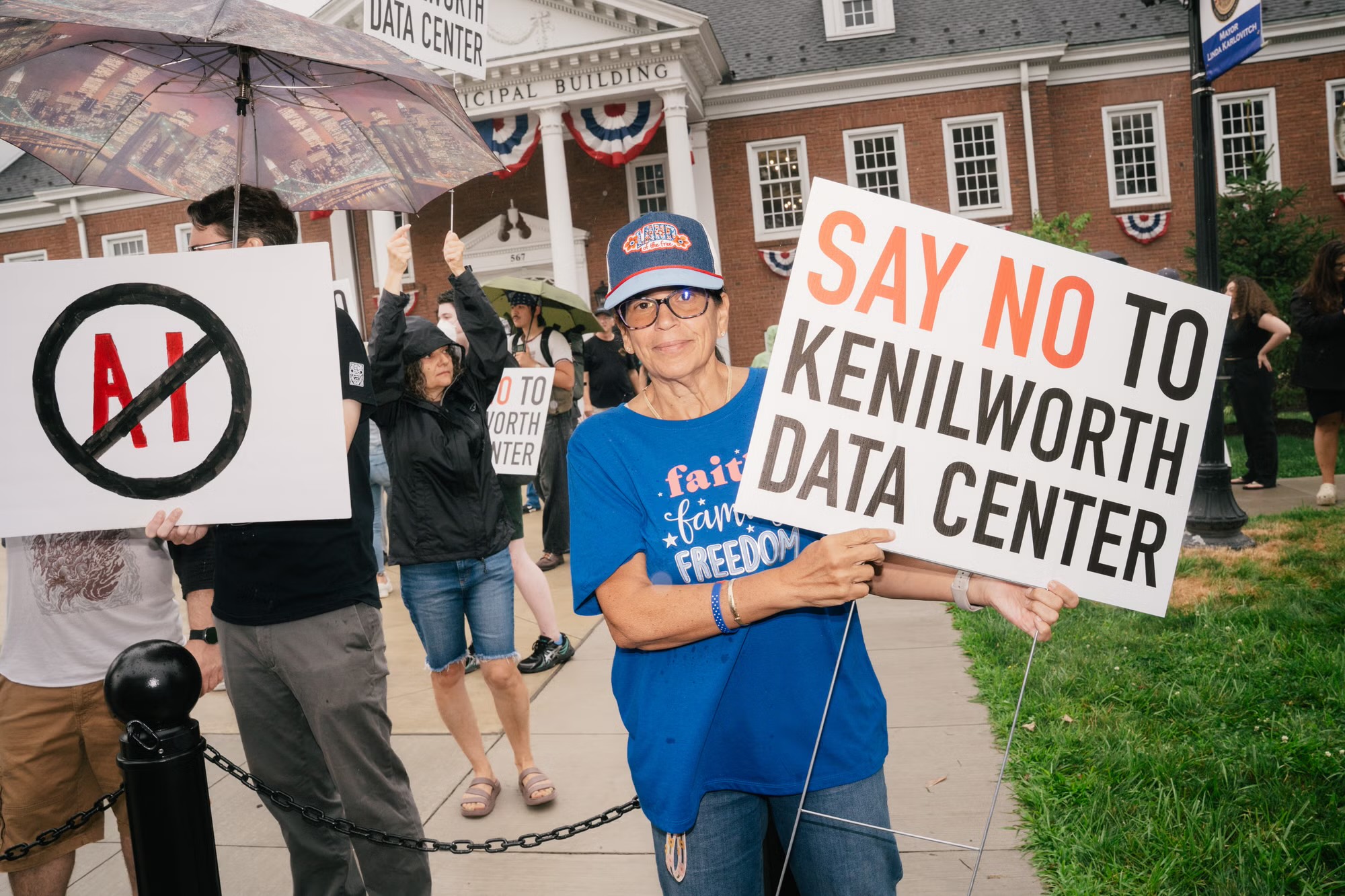 A protester outside a municipal building holds a sign reading Say No to Kenilworth Data Center